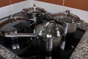 saucepan set with glass lids on a 4 burner glass kitchen hob
