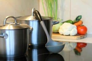close up of large saucepans being used on electric cooktop